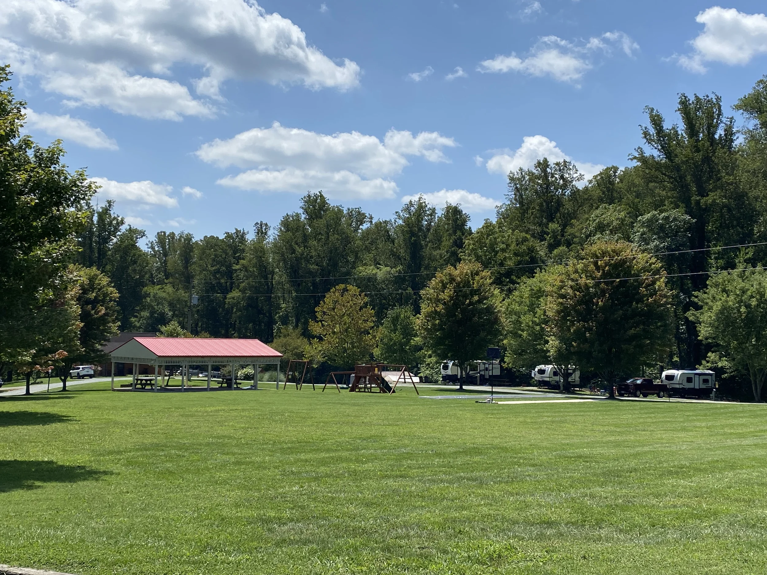 a grassy field with a pavillion surrounded by trees